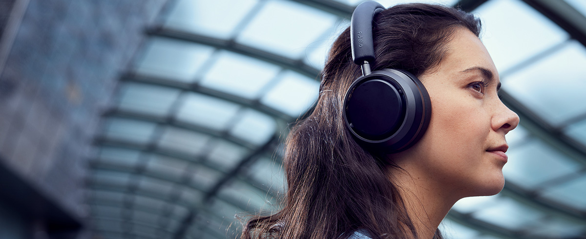 Ženska, ki na potovanju uživa v glasbi s slu&scaron;alkami Philips L4